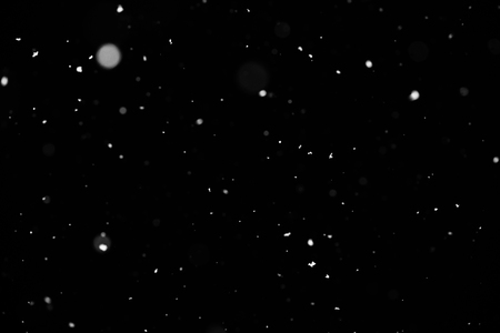 Snowstorm texture. Bokeh lights on black background, shot of flying snowflakes in the airの写真素材