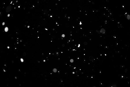 Snowstorm texture. Bokeh lights on black background, shot of flying snowflakes in the airの写真素材