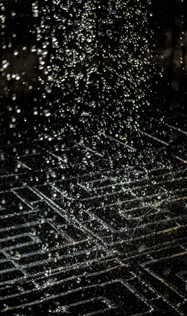 Water splash in dark with a drops of water flying, defocused bokeh.の写真素材