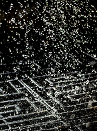 Water splash in dark with a drops of water flying, defocused bokeh.
