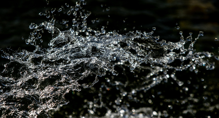 water drops in the air on a dark bokeh backgroundの写真素材