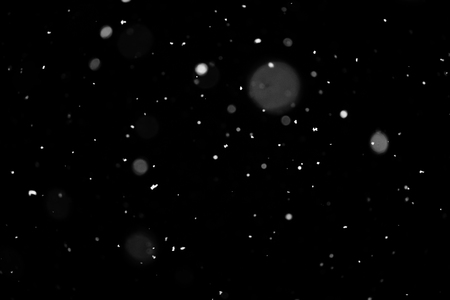 Snowstorm texture. Bokeh lights on black background, shot of flying snowflakes in the airの写真素材