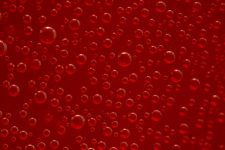 round air droplets in water on a red backgroundの写真素材