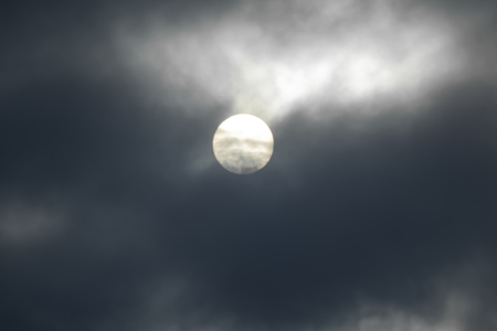 The sun is covered with dark clouds, the sun defocused in the clouds.