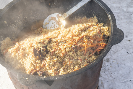 Pilaf cooked on the street in a large cauldron. Rice porridge with meat carrots onion garlic.の写真素材