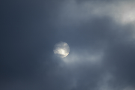 The sun is covered with dark clouds, the sun defocused in the clouds.