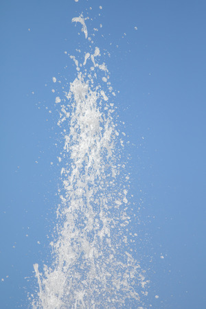 Spray of water fountain against the blue sky. Water splashes are out of focus.の写真素材