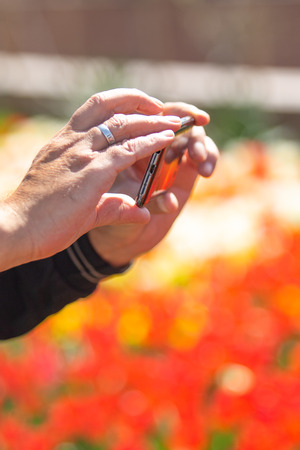 Man's hands are holding a cell phone for a photo on the streetの写真素材