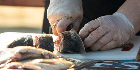 On the table, clean the fish from the scales and remove the entrails. Peeling and fillet of fresh fish that use a knife to clean the fish. Seafood cooking.の写真素材