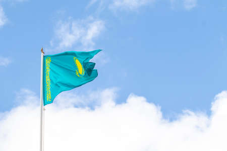 Flag of the Republic of Kazakhstan against the blue sky, wind.