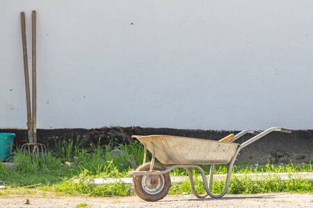 Wheelbarrow. ld yellow Trolley for construction. Using feathers, stones, sand, cement and others.の写真素材