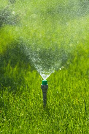 Irrigation System Watering the green grass with bokeh background.の写真素材