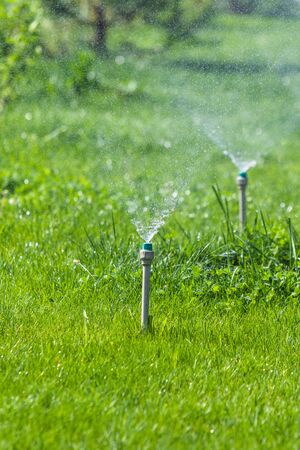 Irrigation System Watering the green grass with bokeh background.の写真素材