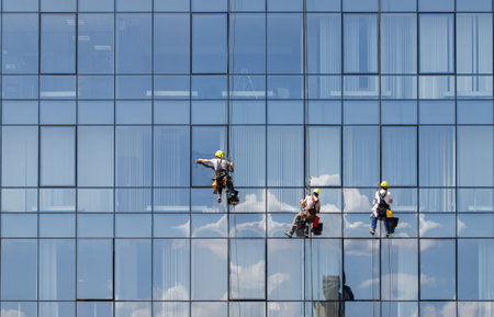 Astana, Kazakhstan - June 08, 2023: Climbers clean glass in a multi-storey glass building.の写真素材