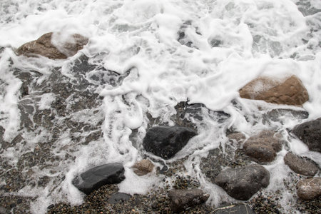 foamy coastal sea wave of a pebble beachの写真素材