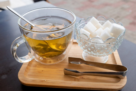 Glass cup of tea with sugar, blurred background, waterfront cafe.の写真素材