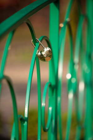 Green metal fence with a padlock in the shape of a heartの写真素材