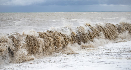 Large waves hit the shore. Storm at sea, storm warning on the coast. Thunderclouds and large sea waves during a storm.の写真素材