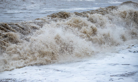 Large waves hit the shore. Storm at sea, storm warning on the coast. Thunderclouds and large sea waves during a storm.の写真素材