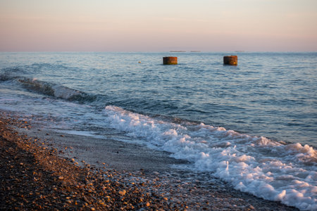 The ocean is calm and the sky is a beautiful shade of pink. The water is a deep blue color and the waves are smallの写真素材