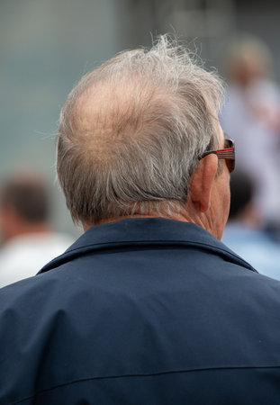 A man with a bald head and glasses is wearing a blue jacket. He is looking at the cameraの写真素材