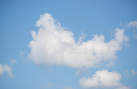 A large fluffy cloud in the sky. The sky is blue and clear. The cloud is white and puffyの写真素材