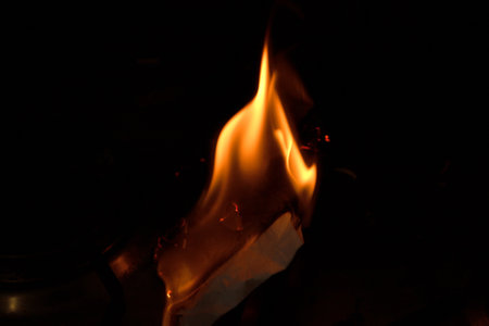 A close up of a flame with a dark background. Concept of warmth and comfort, as well as a feeling of danger and unpredictability. The flame is the focal point of the imageの写真素材