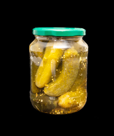 A jar of pickles with three pickles inside. The jar is green and clear. The pickles are in a pickle brineの写真素材