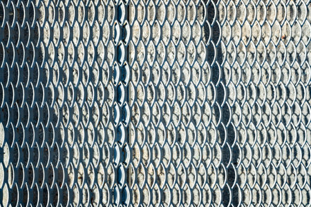 A metal fence with a blue and white pattern. The fence has a diamond patternの写真素材