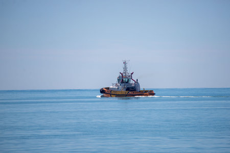 A large yellow boat is on the water. The sky is clear and the water is calm. The boat is moving slowly and is surrounded by the blue oceanの写真素材