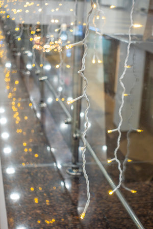 A long string of lights hangs from the ceiling, creating a warm and inviting atmosphere. The lights are lit up, casting a soft glow on the surrounding area. Concept of comfort and relaxationの写真素材