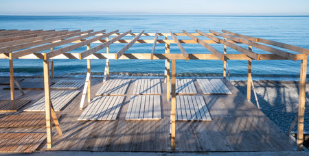 A wooden structure with a roof and a beach in the background. The structure is empty and the beach is calmの写真素材