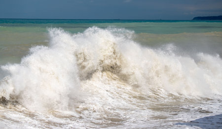 The ocean is rough and the waves are high. The water is white and the sky is blueの写真素材