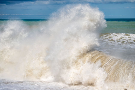 The ocean is rough and the waves are high. The water is white and the sky is blueの写真素材