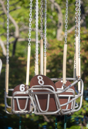 A row of swings with numbers 8, 6, and 7 on them. The swings are suspended from chains and are emptyの写真素材