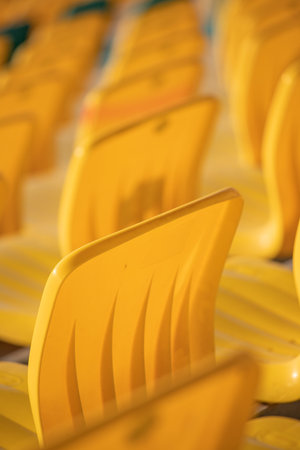 A row of yellow chairs are empty. The chairs are arranged in a row, with some of them facing the camera. The chairs are all the same color and size, and they are all emptyの写真素材