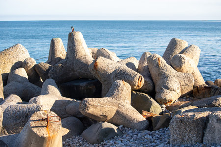 A rocky shoreline with a large body of water in the background. The rocks are piled up in a way that creates a barrier between the land and the water. The scene is calm and peacefulの写真素材