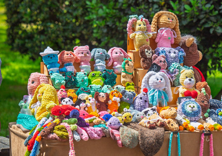 A table full of stuffed animals, including a variety of animals and a few teddy bears. The table is covered in a colorful assortment of knitted items, creating a vibrant and playful atmosphereの写真素材