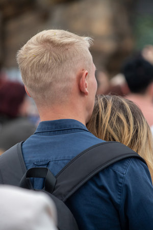 A man and a woman are standing next to each other, with the man looking at the woman. The man is wearing a blue shirt and a backpackの写真素材