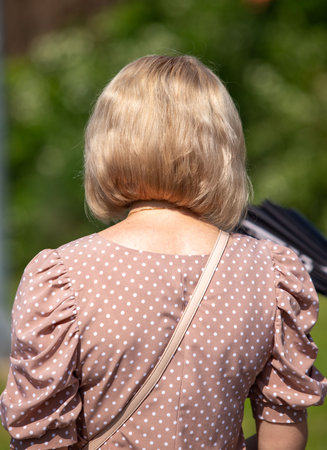 A woman wearing a polka dot dress and a purse. She has a short haircut. The image has a light and cheerful moodの写真素材