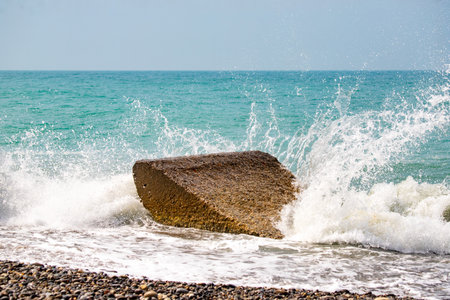 A large rock is in the ocean, and the water is splashing around it. The scene is calm and peaceful, with the waves gently lapping at the shoreの写真素材