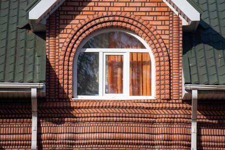 A window in a brick building with a green roof. The window is rectangular and has a white frameの写真素材