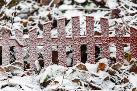 A red fence covered in snow. The fence is made of wood and has a white trim. The snow is covering the ground and the fence, giving it a wintery and peaceful atmosphereの写真素材