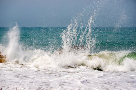 The ocean is rough and the waves are high. The water is white and the sky is blueの写真素材