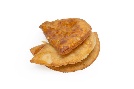 A stack of fried pastries with a golden brown crust. The pastries are piled on top of each other,...