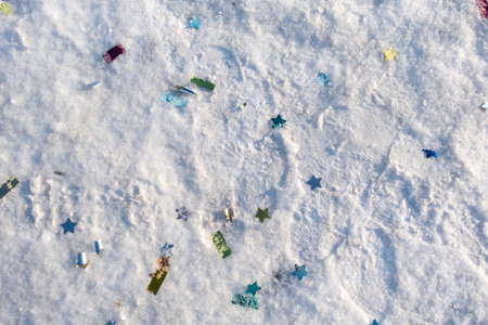A snow covered ground with many stars and pieces of paper scattered on it. The paper pieces are of...