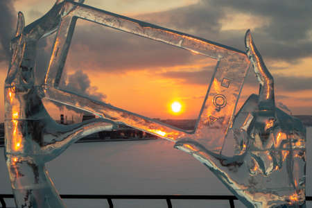 ice sculpture of hands with phone at sunsetの写真素材