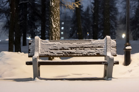 bench in a night snowy park under the light of lanternsの写真素材