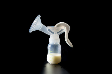 Baby bottle with milk and Manual breast on black background. Breast pump. Breastfeeding.の写真素材