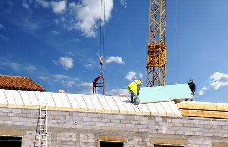 Laying insulation boards on the roof of a house under construction.